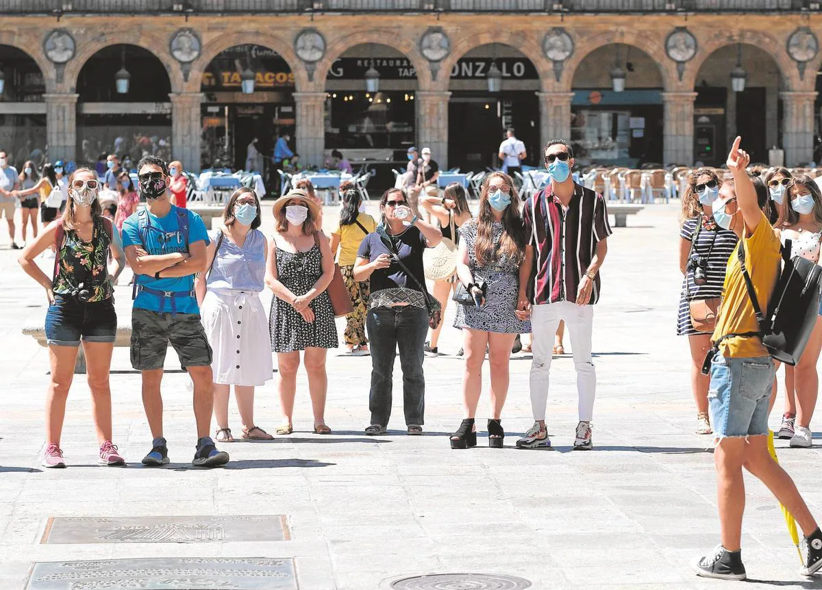 Un grupo de turistas atiende a las explicaciones de un guía en la Plaza Mayor de Salamanca.