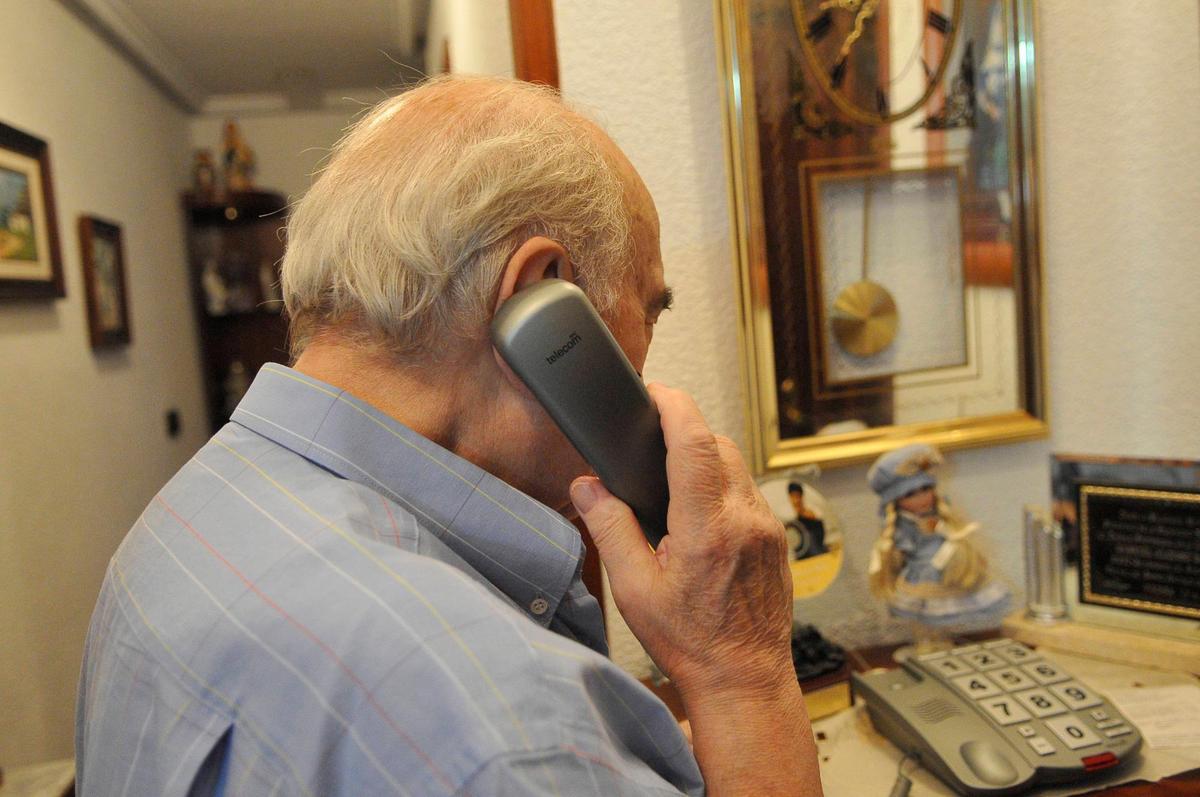 Un hombre realizando una llamada desde su teléfono fijo.