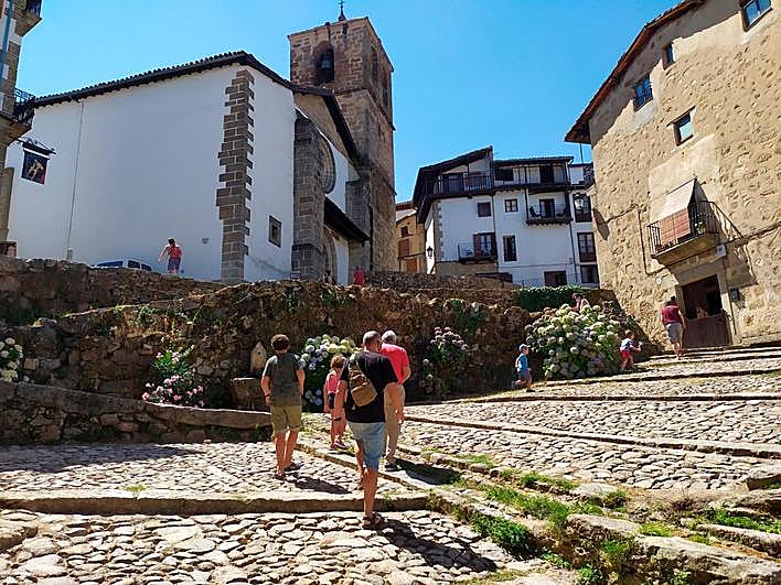 Imagen de la Cuesta de la Romana con vecinos y turistas disfrutando del verano en Candelario.