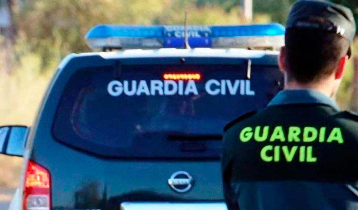 Miembro de la Guardia Civil junto a su coche.