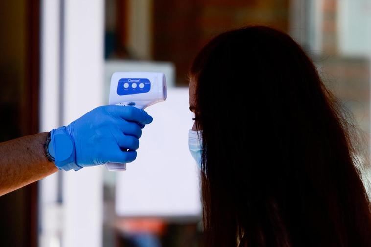 Un sanitario toma la temperatura a una mujer.