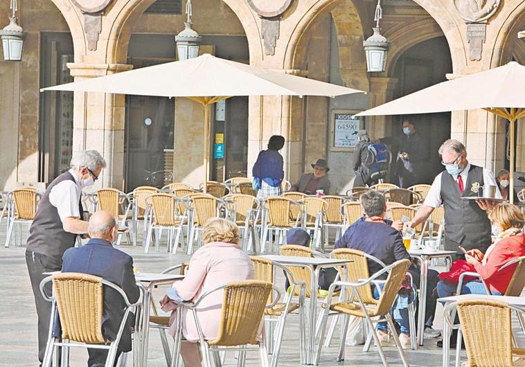 Dos camareros trabajando en una terraza de la Plaza Mayor.