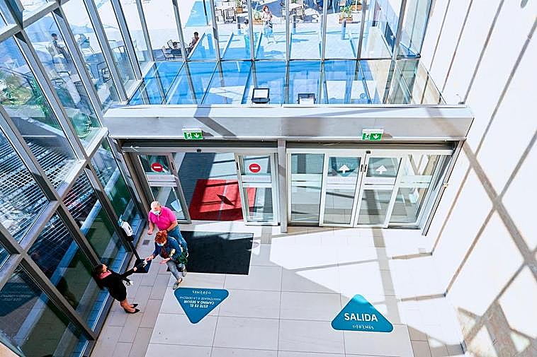 Dos clientes del centro comercial El Tormes hacen uso del gel hidroalcohólico antes de iniciar sus compras.