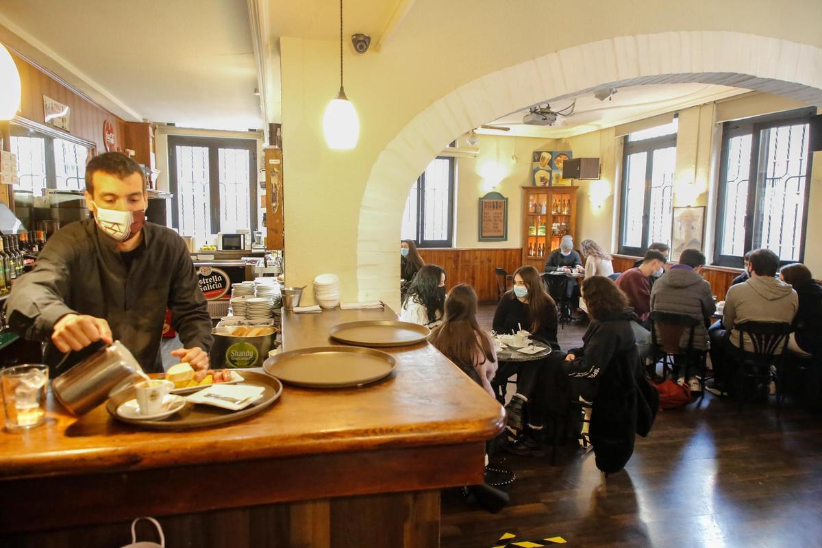 Un camarero sirve un café en su establecimiento.