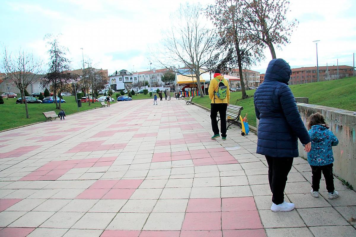 Familias y niños jugando cerca de uno de los parques cerrados de Carbajosa.