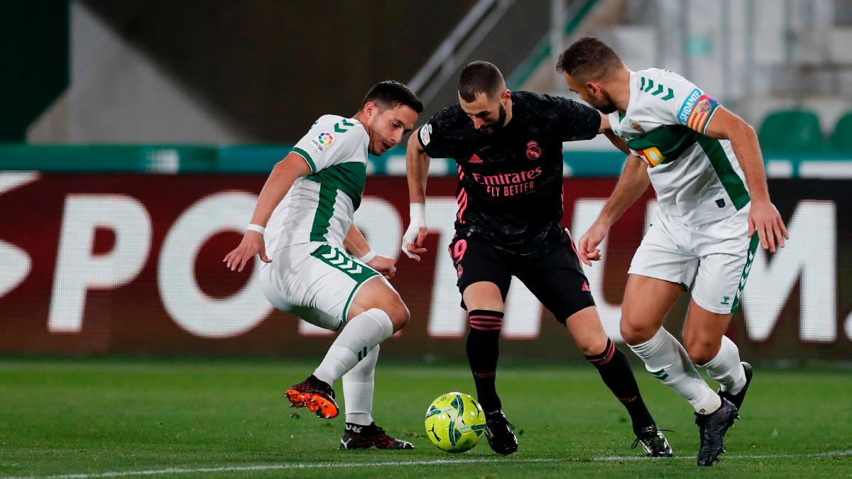 Benzema trata de zafarse de dos defensas del Elche.