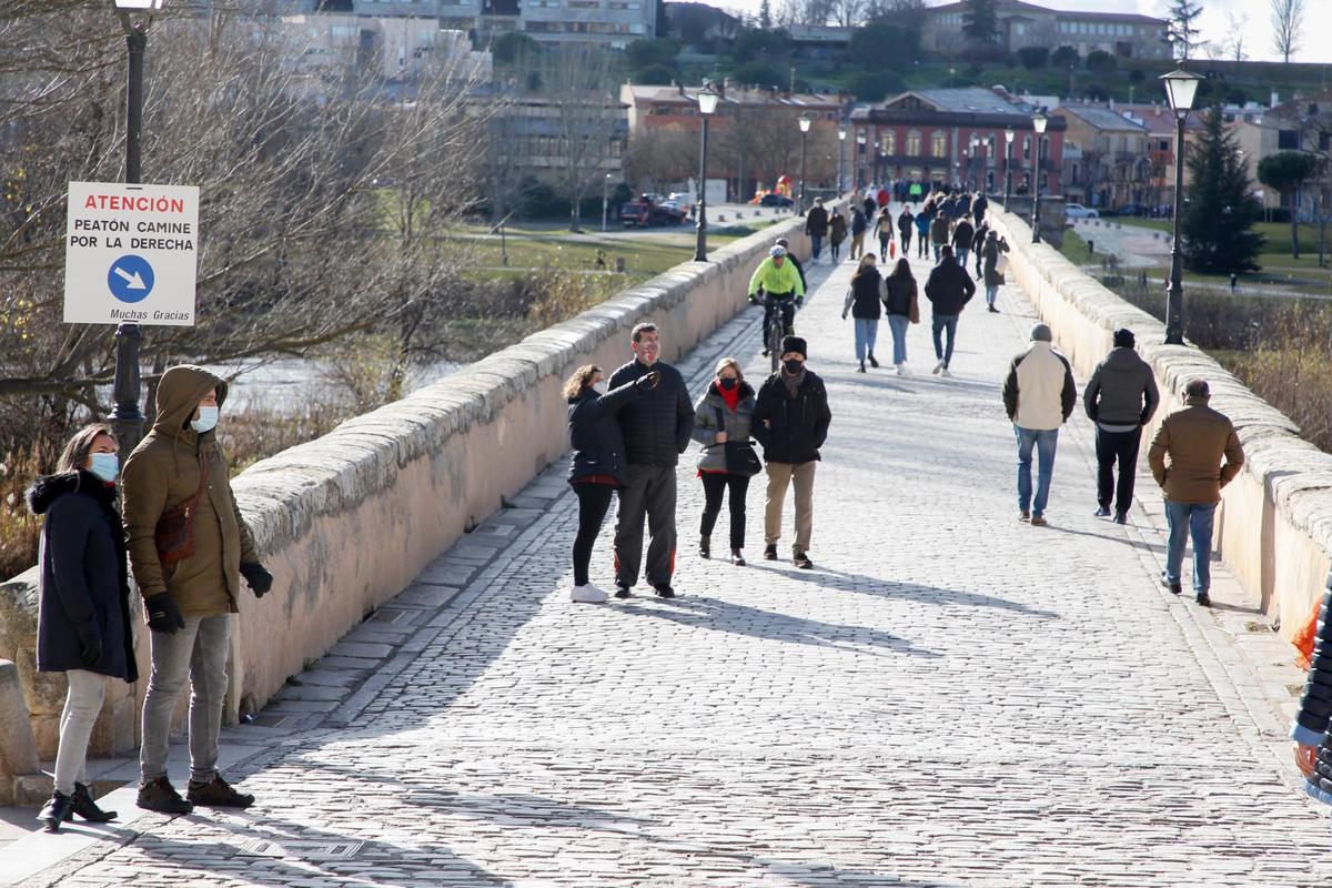 Varias personas paseando por el Puente Romano de la ciudad.