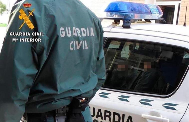 Un agente de la Guardia Civil junto a un coche patrulla.