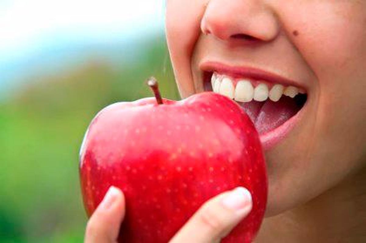 Una mujer comiendo una manzana.