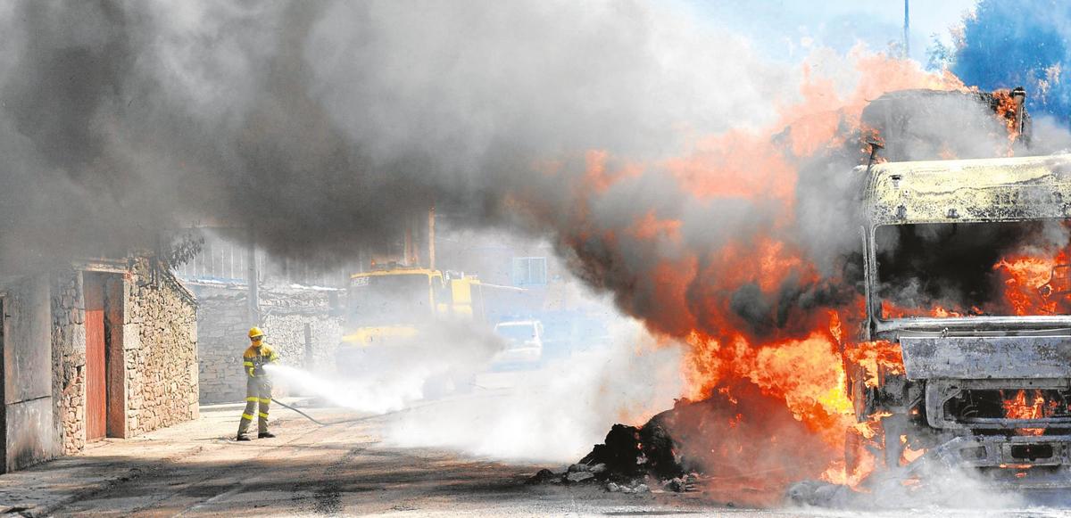 Un bombero extingue las llamas en el camión tras comenzar a arder en pleno casco urbano de Vitigudino.