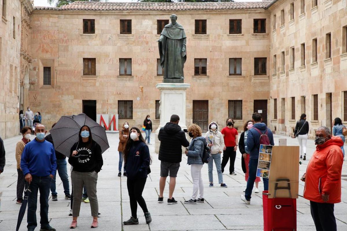Varias personas con mascarilla ante la fachada de la Universidad de Salamanca.