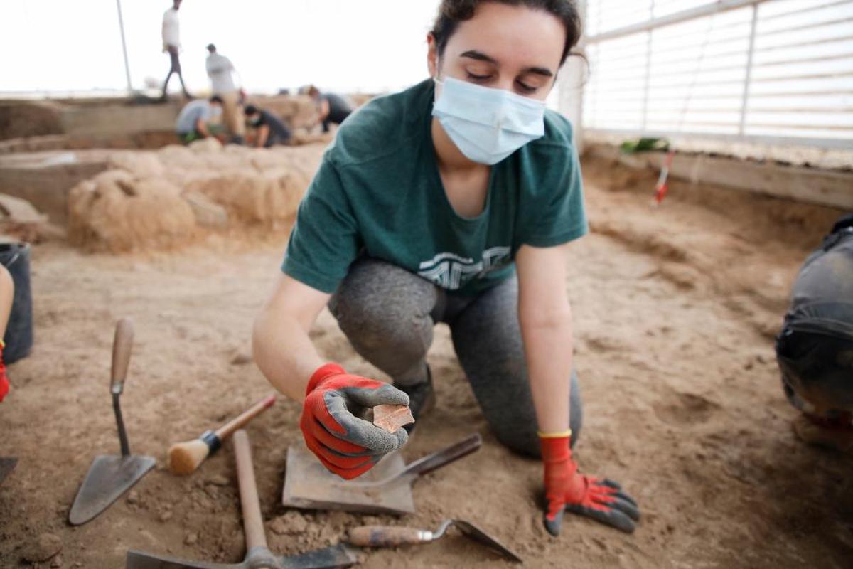 Una joven arqueóloga muestra el fragmento de cerámica que ha encontrado