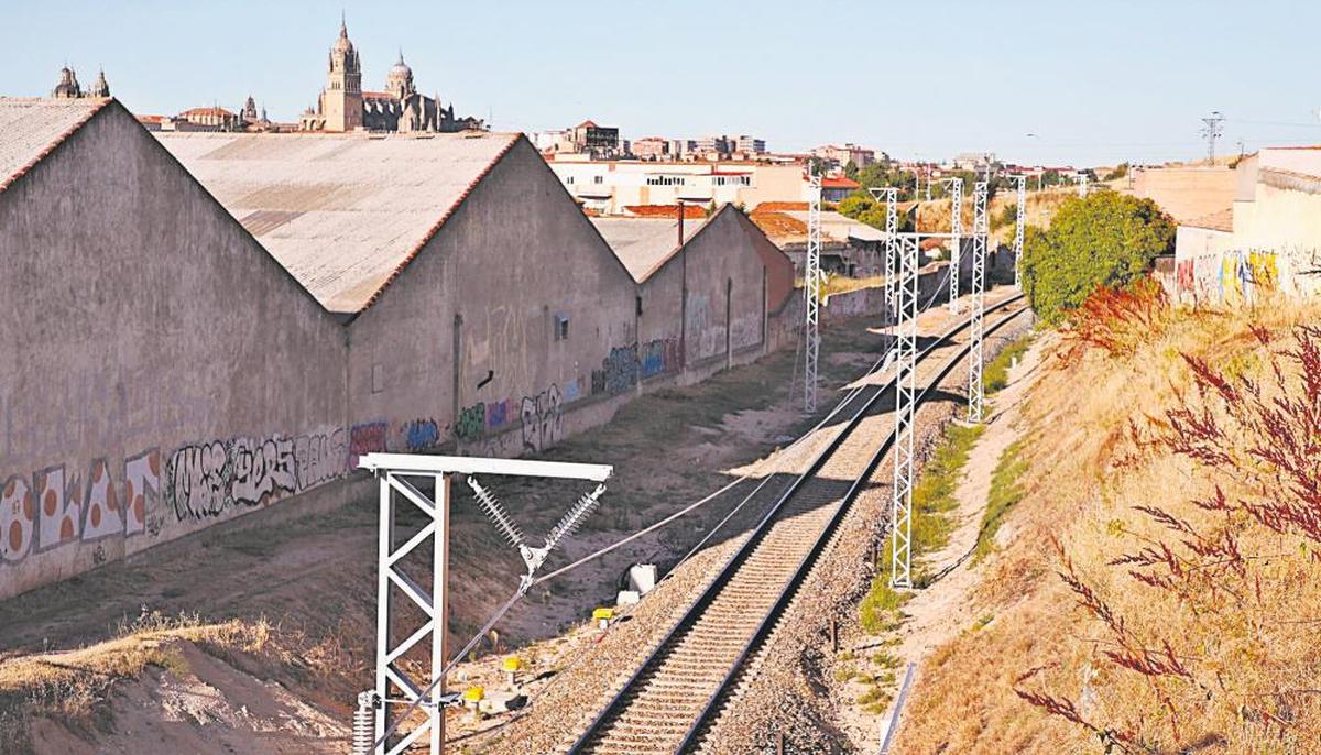 Tramo de la vía entre Salamanca y Fuentes de Oñoro con los postes para la electrificación colocados y al fondo, la capital salmantina.