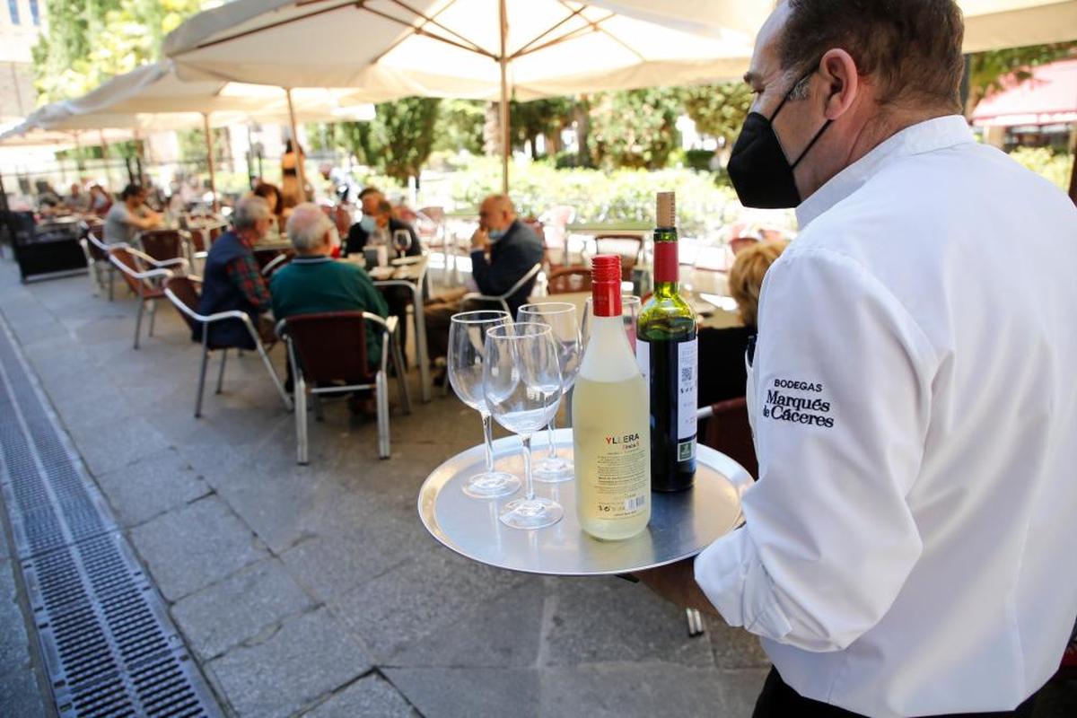 Un camarero se dirige a servir a unos clientes en una terraza en la capital.