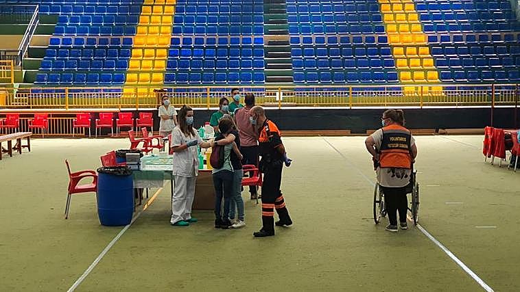 Momento en el que María Martín es abrazada por su hermana mientras el personal sanitario pone la vacuna