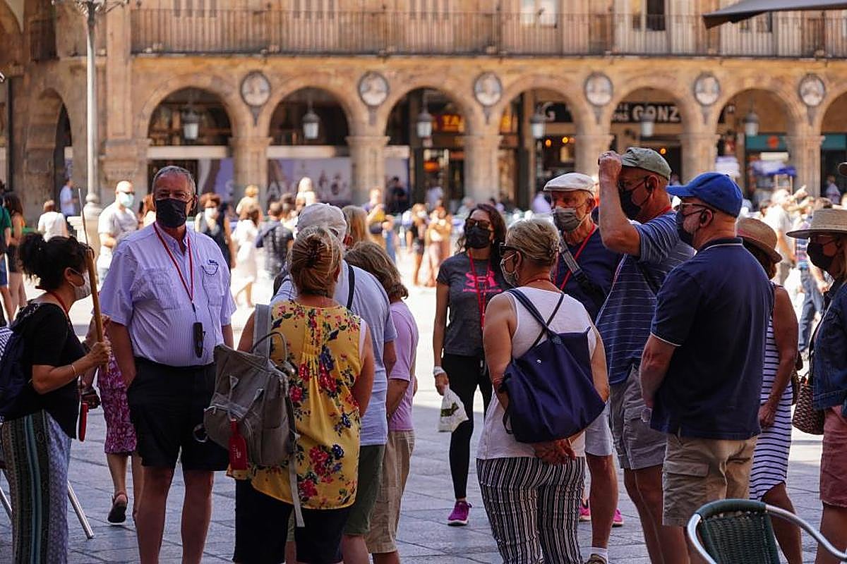 Un grupo de turistas internacionales atiende a las explicaciones de una guía en la Plaza Mayor.
