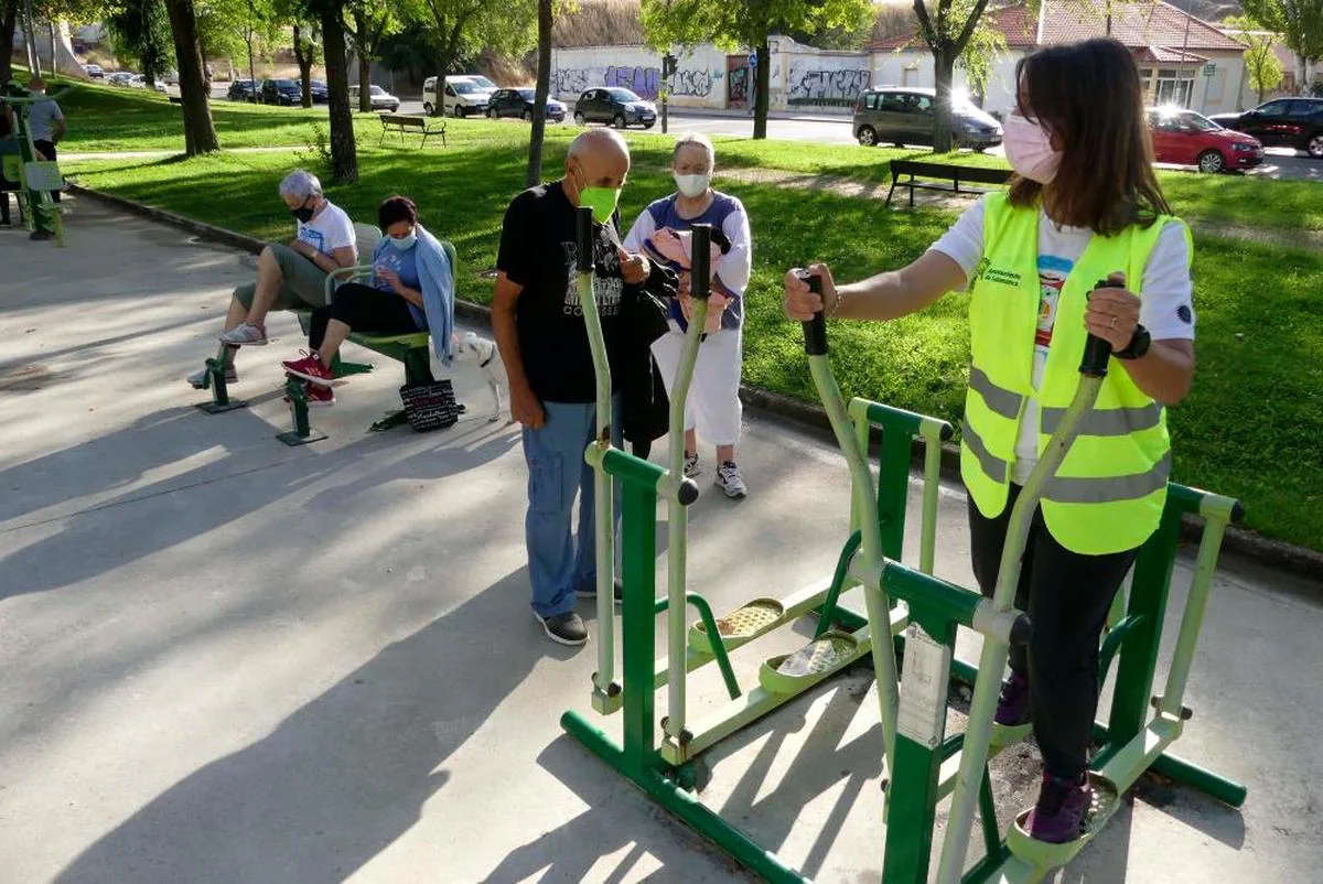 La monitora, Marta Romero, explica el funcionamiento de los aparatos biosaludables a los usuarios del parque Würzburg.