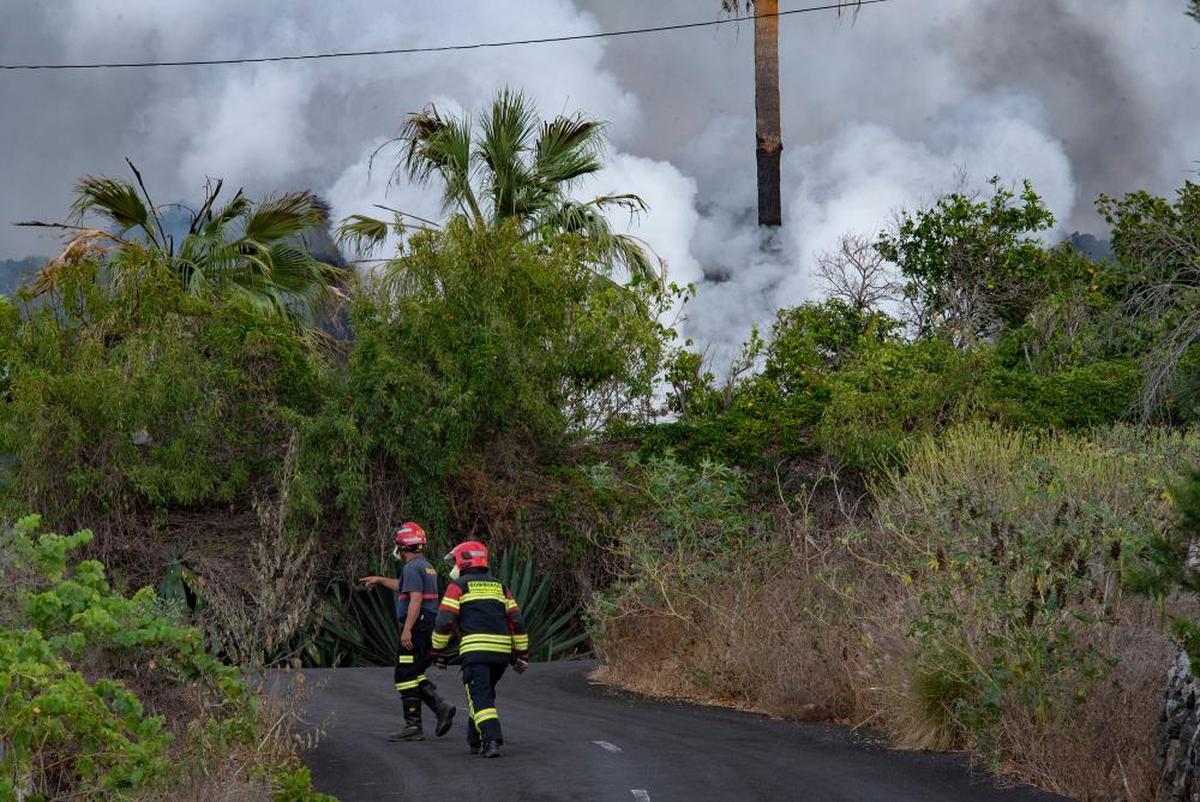 Dos bomberos trabajan en una de las zonas afectadas por el volcán