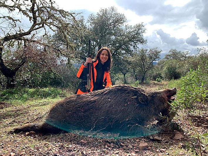 Lorena G. Vizcaíno, autora del artículo, con un gran ejemplar de jabalí abatido durante una montería.