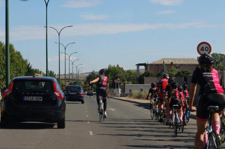 Un coche adelanta a un grupo de ciclistas.