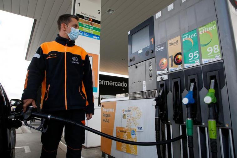 El empleado de una estación de servicio reposta el vehículo de un cliente