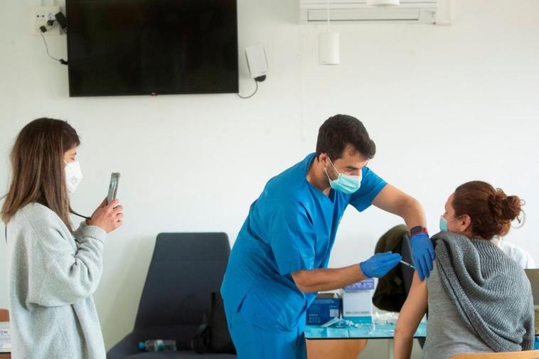 Un sanitario administrando una vacuna a una joven.