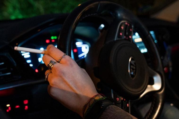 Una persona fumando en el coche.