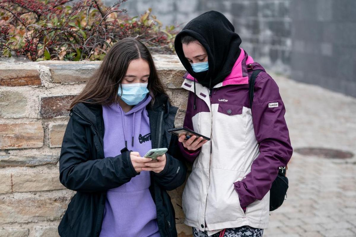 Dos personas pasean con mascarilla por la vía pública.