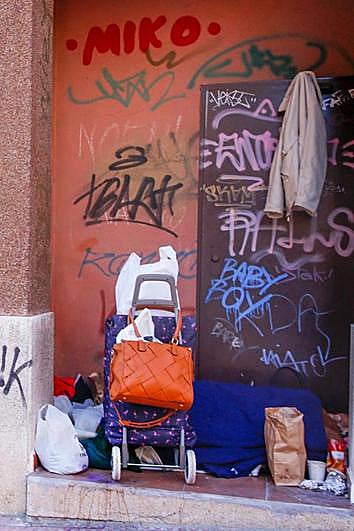 Un sintecho tapado con una manta en el rellano de una puerta