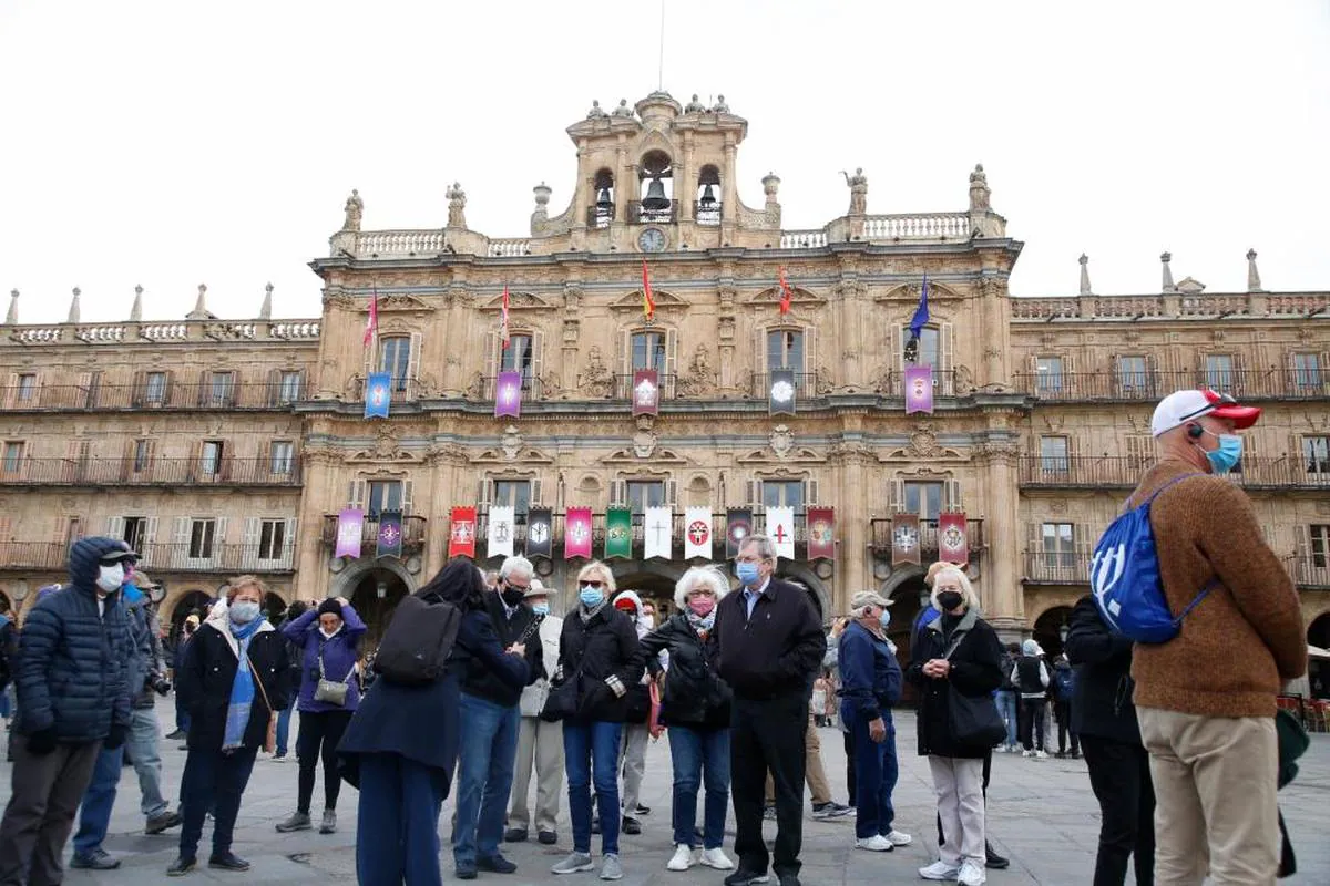 Un grupo de turistas atiende las explicaciones de una guía en la Plaza Mayor de Salamanca.