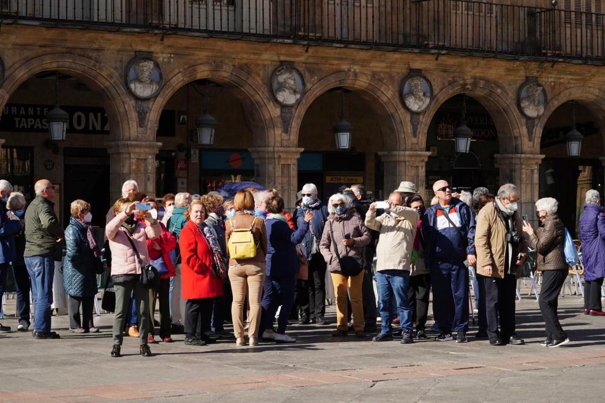 Grupo de turistas tomando fotos en la Plaza Mayor.