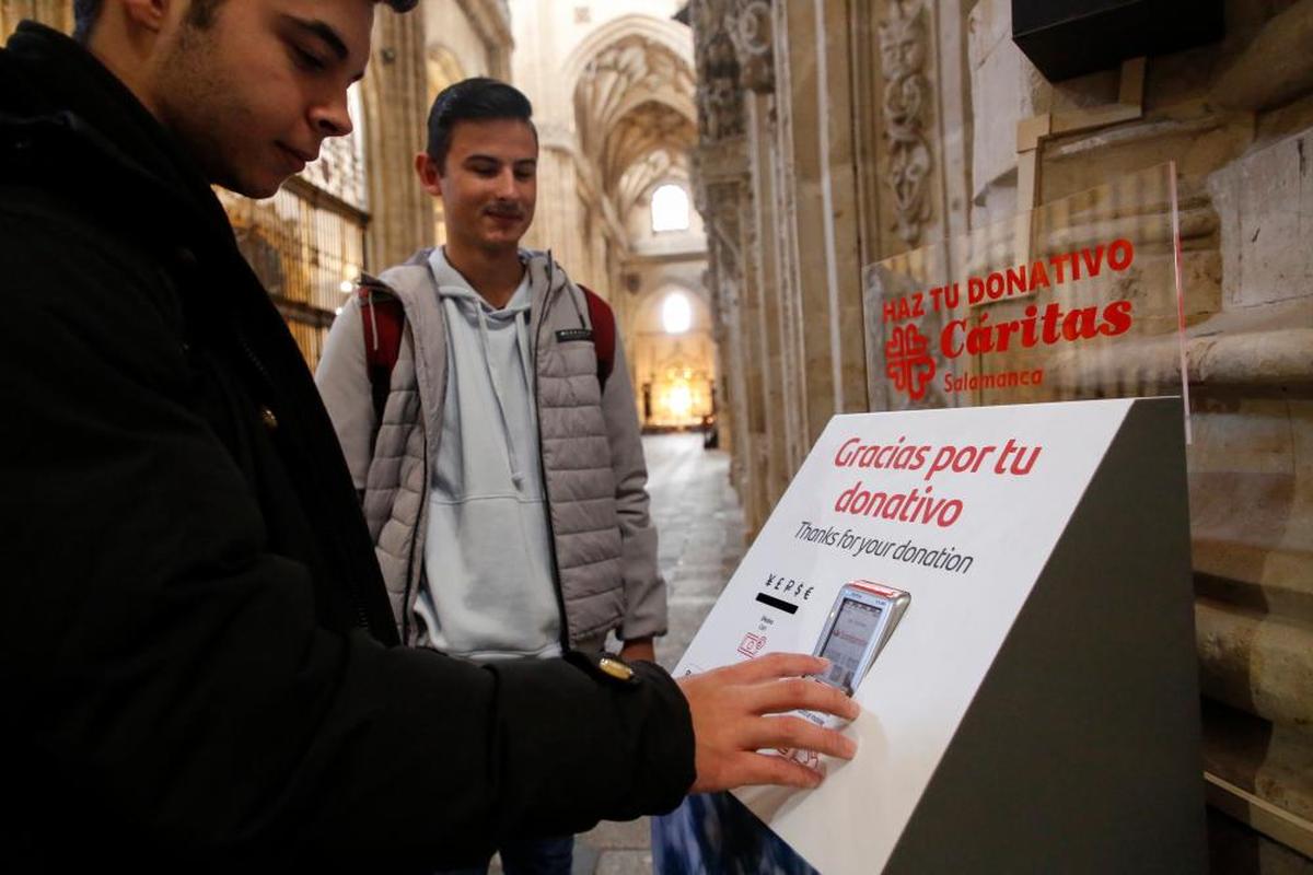 Dos jóvenes se disponen a donar con tarjeta en la Catedral.