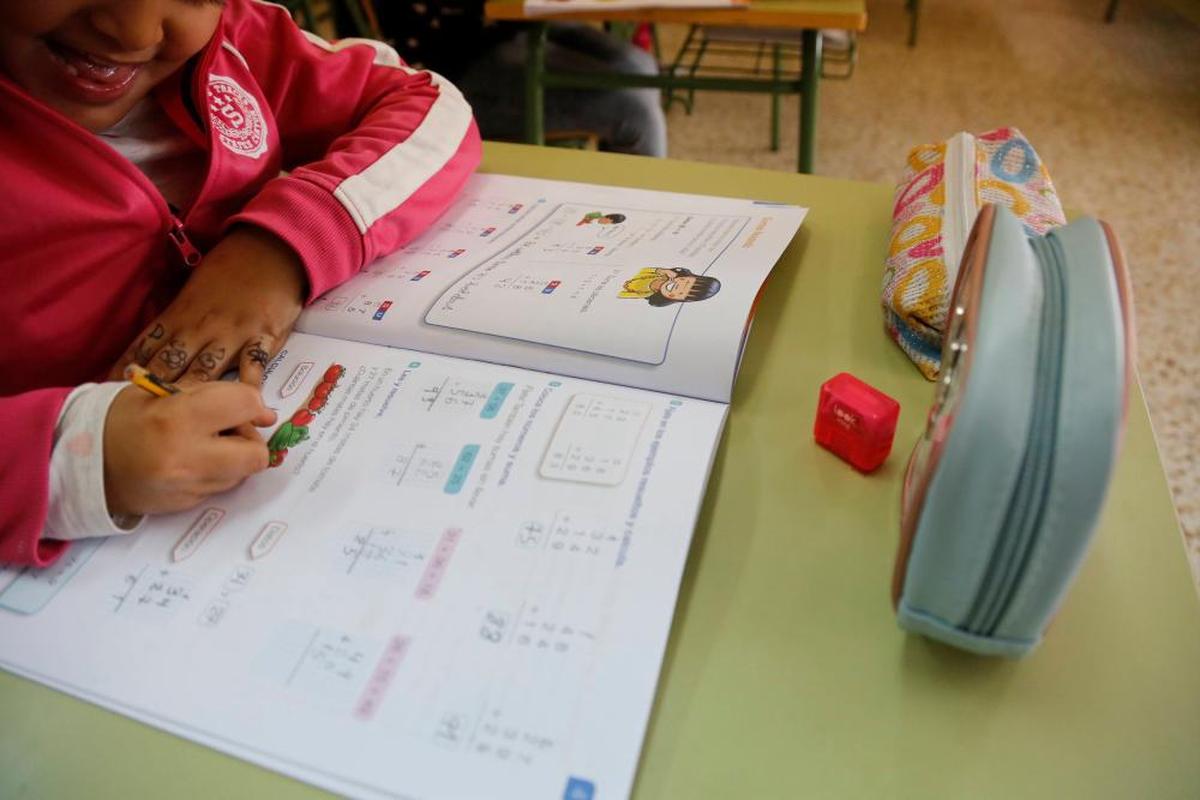 Una niña de Primaria realizando cuentas en un libro de Matemáticas.