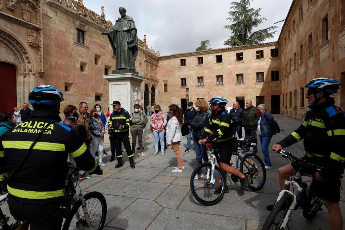 Efectivos de la Policía Turística junto a un grupo de turistas en el Patio de Escuelas.