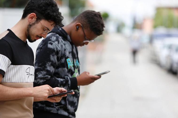 Jóvenes consultando internet en el teléfono móvil.