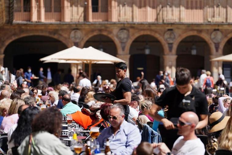 Un camarero, pasa entre los clientes sentados en una terraza de la Plaza Mayor.