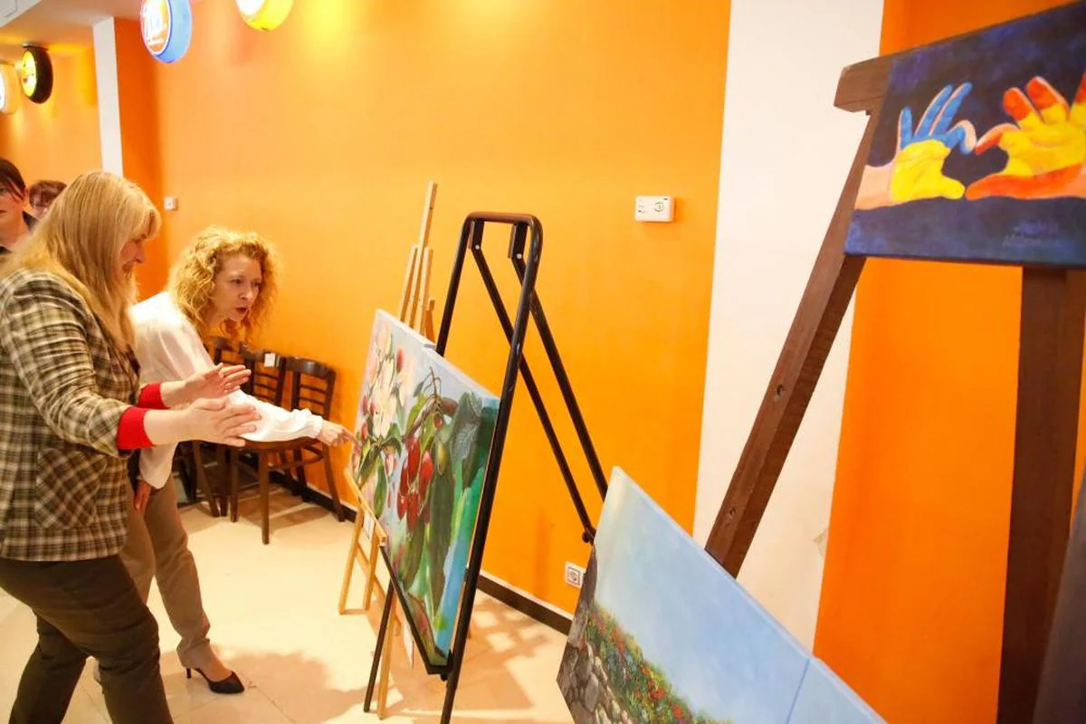 La refugiada Anzhela Melnykova muestra su pintura a Ana Suárez