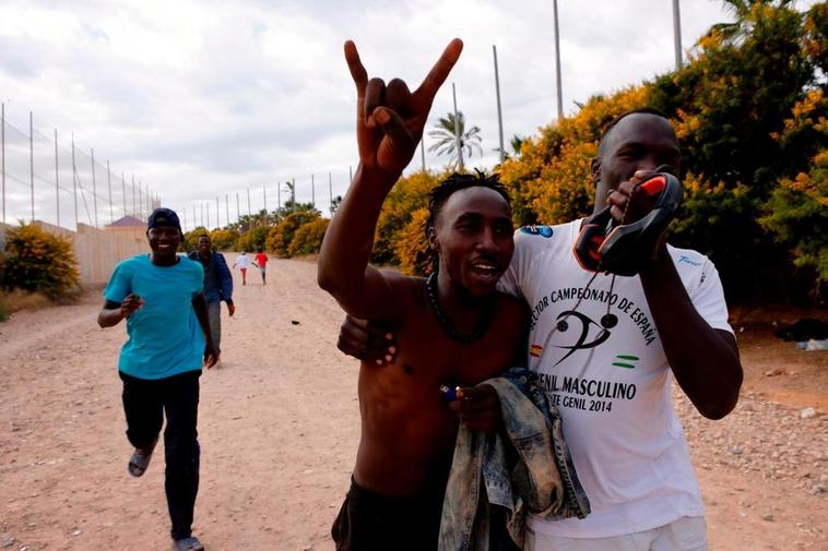 Varios migrantes celebran el salto de la valla de Melilla