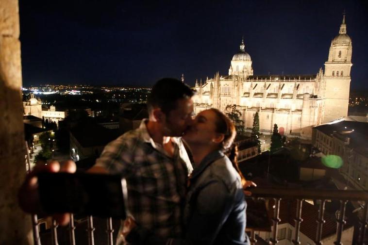 Un pareja se fotografía en las torres de la Clerecía con la Catedral iluminada de fondo