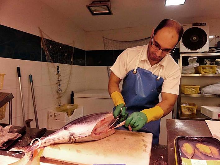 Dependiente de una pescadería del Mercado Central trabajando en un bonito.