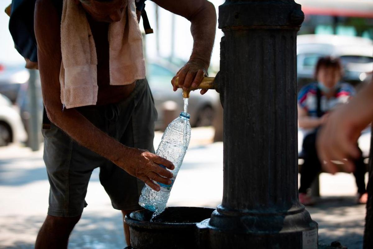 Un hombre rellena una botella de agua en una fuente