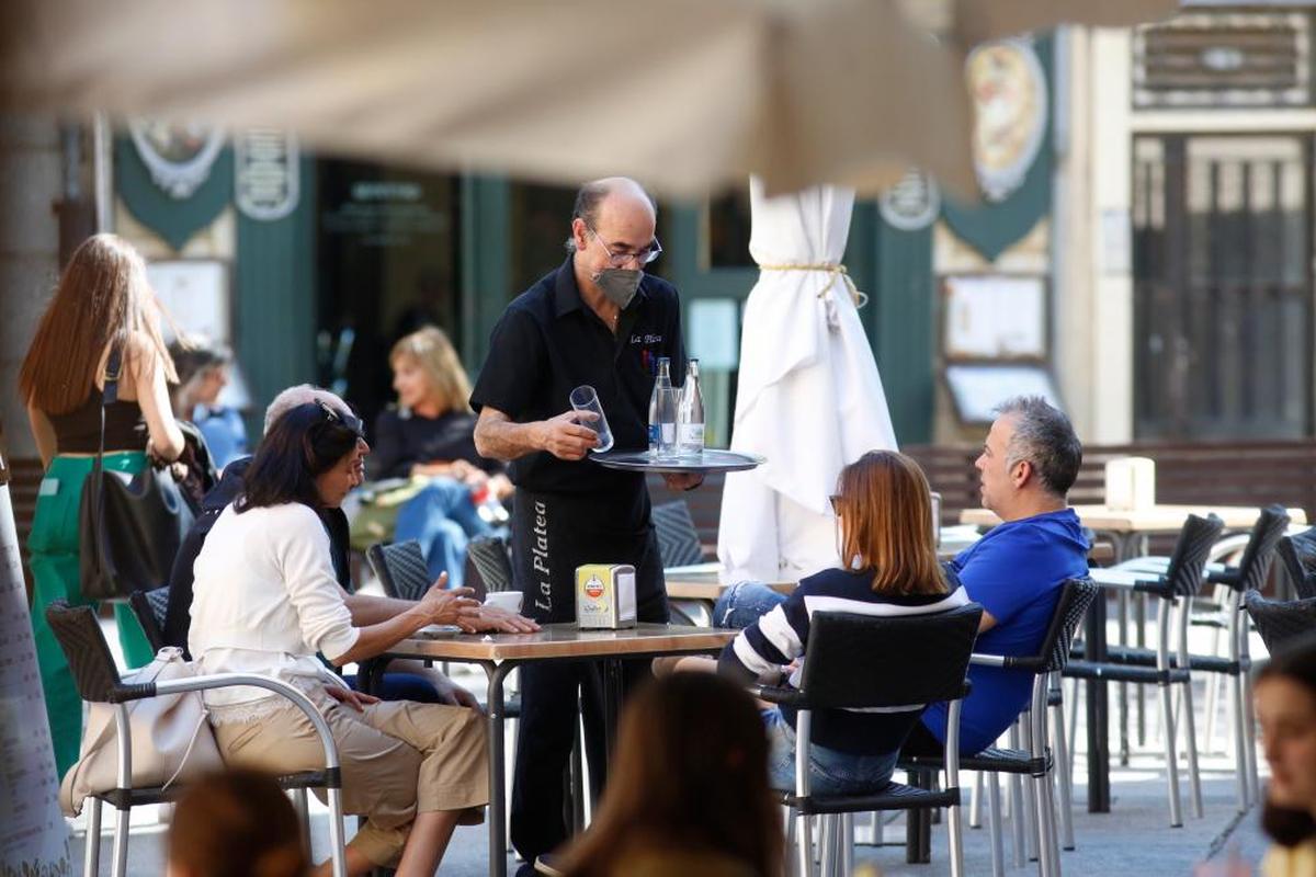 Un camarero atiende a los clientes sentados en la mesa de una terraza del centro de la ciudad.