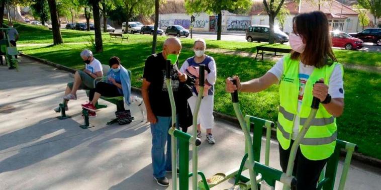 La monitora, Marta Romero, explica el funcionamiento de los aparatos biosaludables a los usuarios del parque Würzburg.