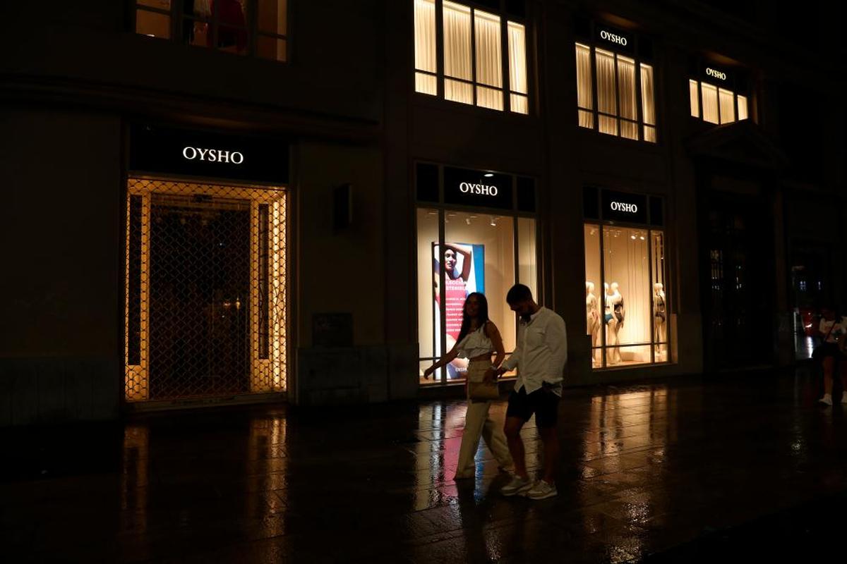 Varias personas caminan por la noche frente a un escaparate en Madrid.