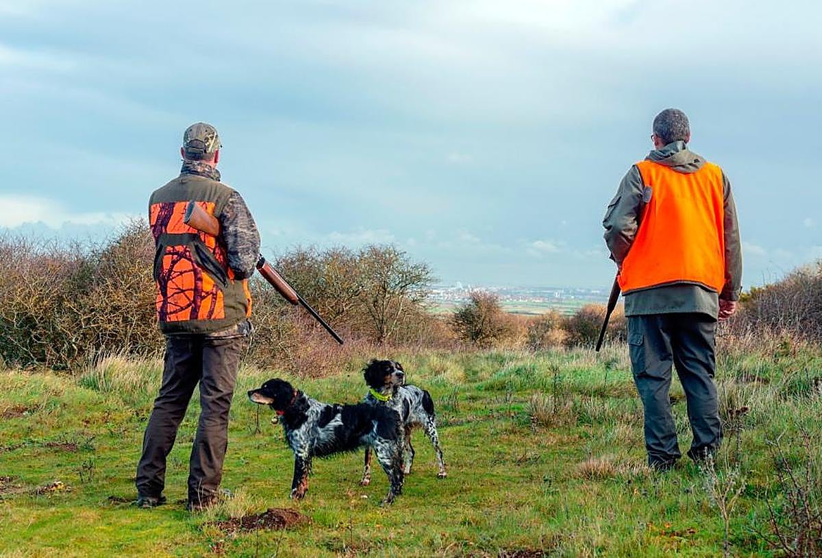 Dos cazadores junto a sus perros