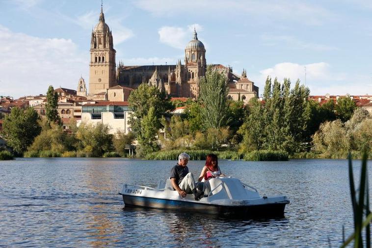 Una pareja aprovecha el buen tiempo para pasear con una barca de pedales por el río.