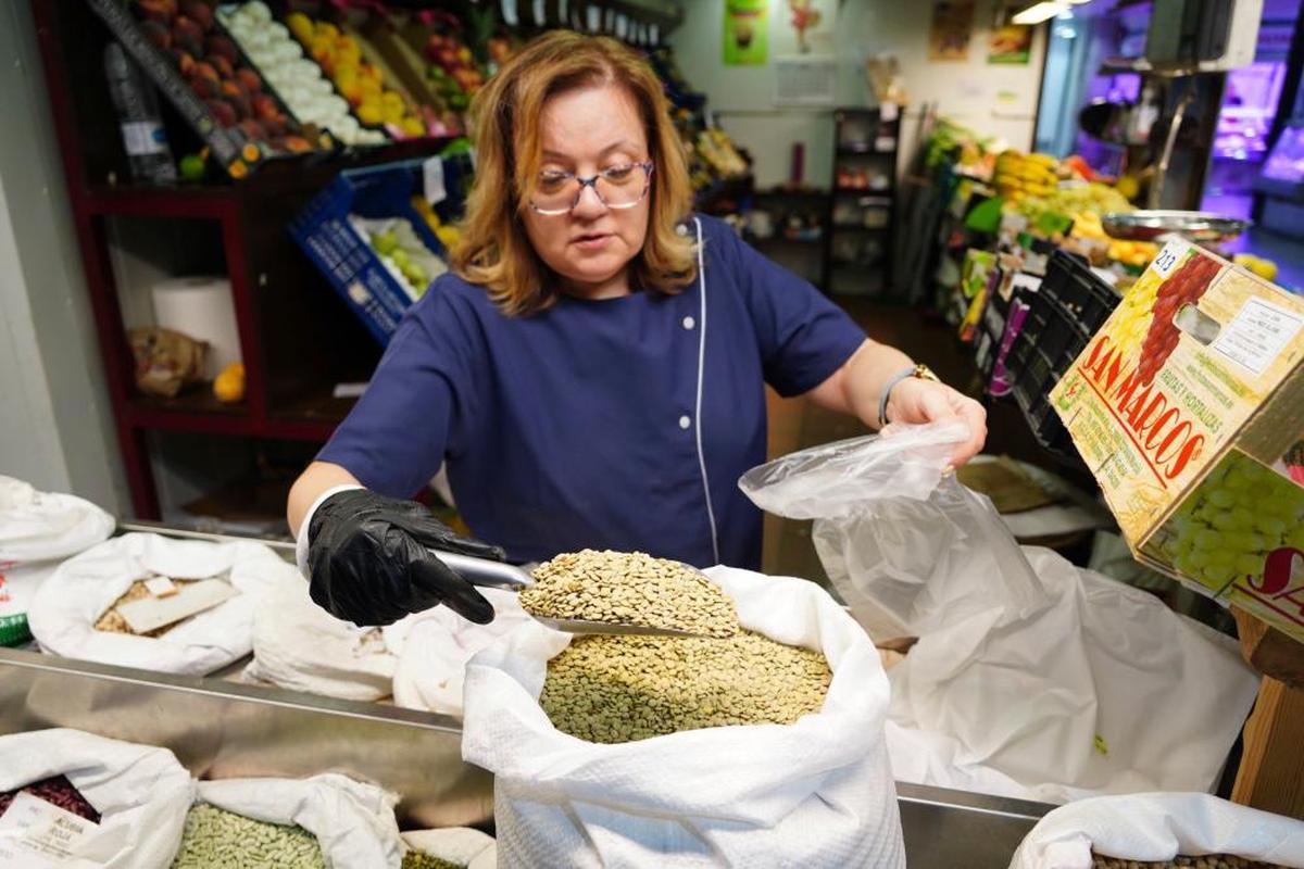 La dependienta de una frutería del Mercado Central sirviendo lentejas