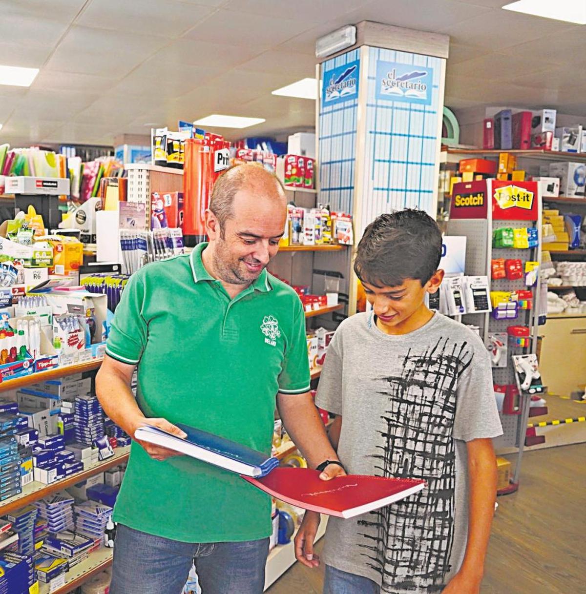 El dependiente de la librería El Secretario ofrece dos cuadernos a un joven.