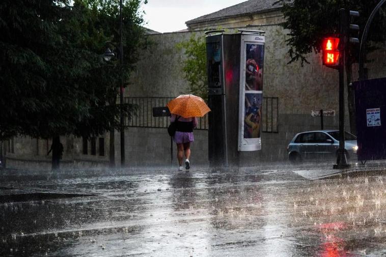 Una persona con paraguas bajo una incesante tormenta.