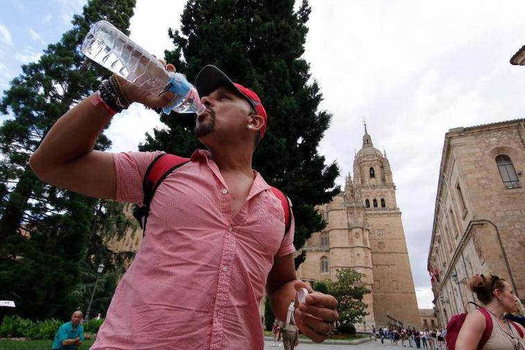 Un turista se hidrata mientras visita el casco histórico de Salamanca.